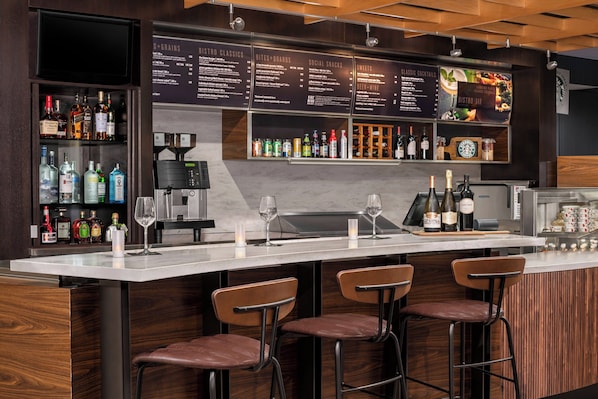 A bar area with a menu board, bar stools, and a variety of bottles.