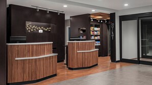 A reception area with two wooden reception desks, a wall-mounted display, and a snack bar with various packaged goods.
