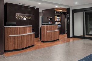 Una zona de recepción con dos mostradores de madera, una pantalla en la pared y un bar de aperitivos con diversos productos envasados.