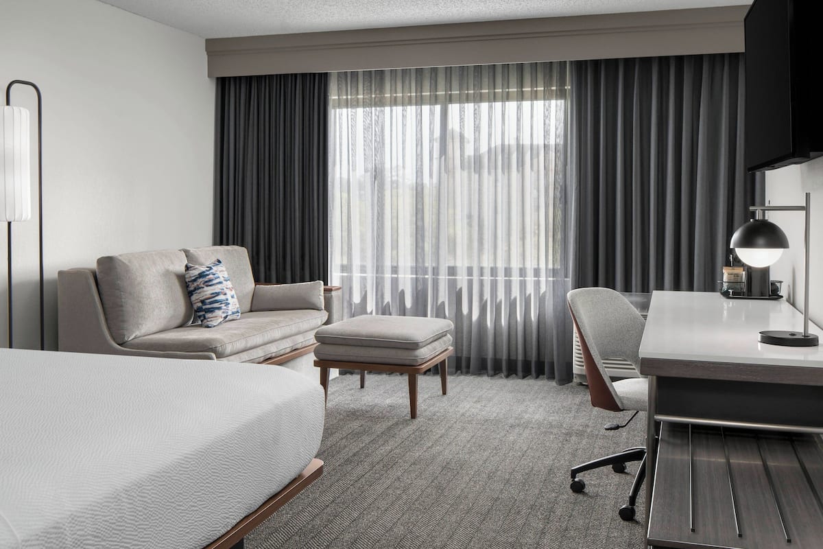 Een hotelkamer met een bed, een slaapbank, een bureau en een stoel.