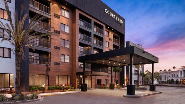 A Courtyard hotel with a modern design, featuring multiple balconies and a covered entrance area.