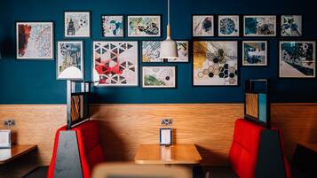 A restaurant with red booths, a wooden table, and a blue wall adorned with framed artwork.