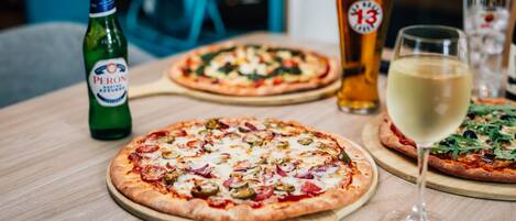 Dos pizzas sobre tablas de madera, con una botella de cerveza y un vaso de cerveza sobre una mesa.
