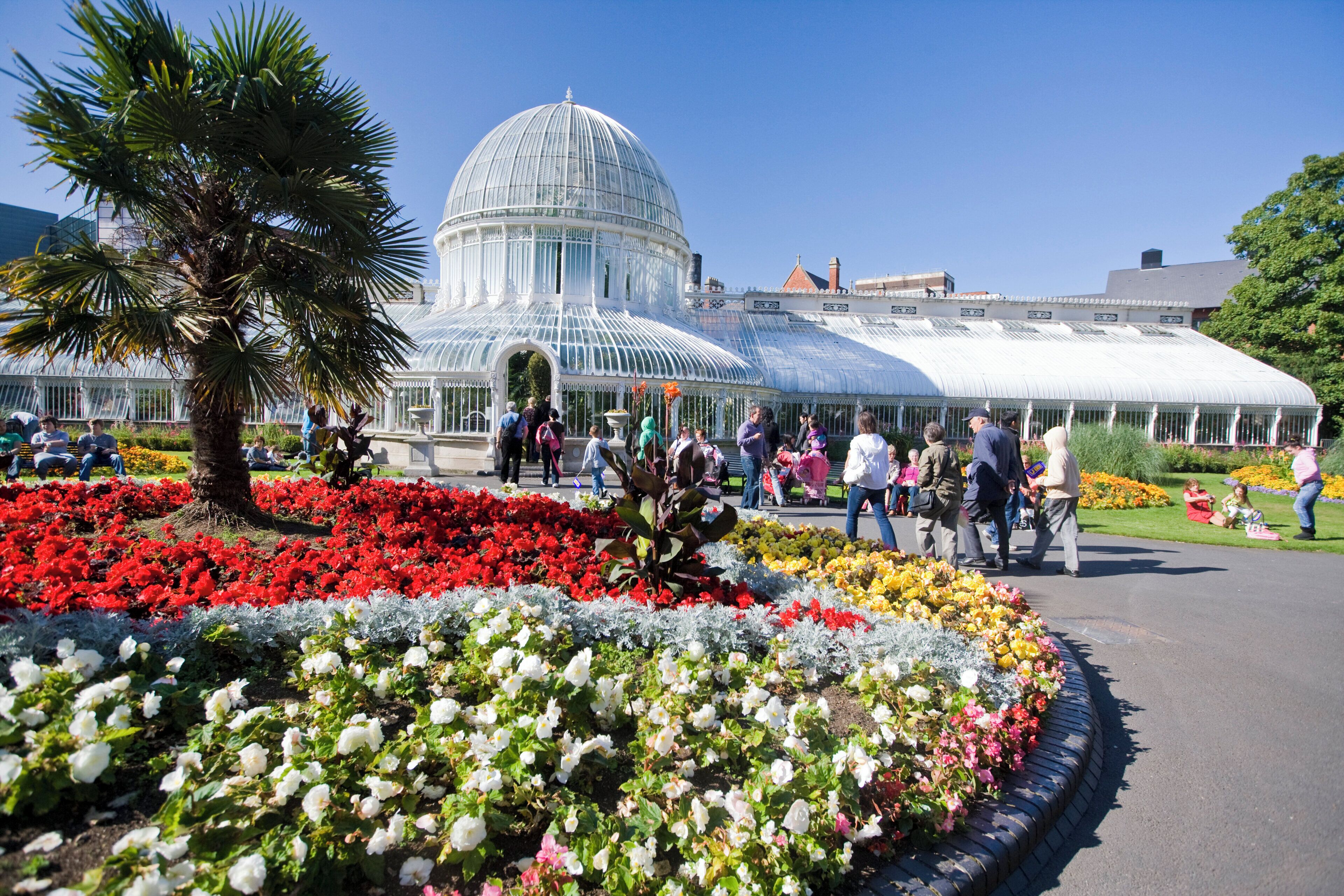 A greenhouse with a dome structure surrounded by flower beds.