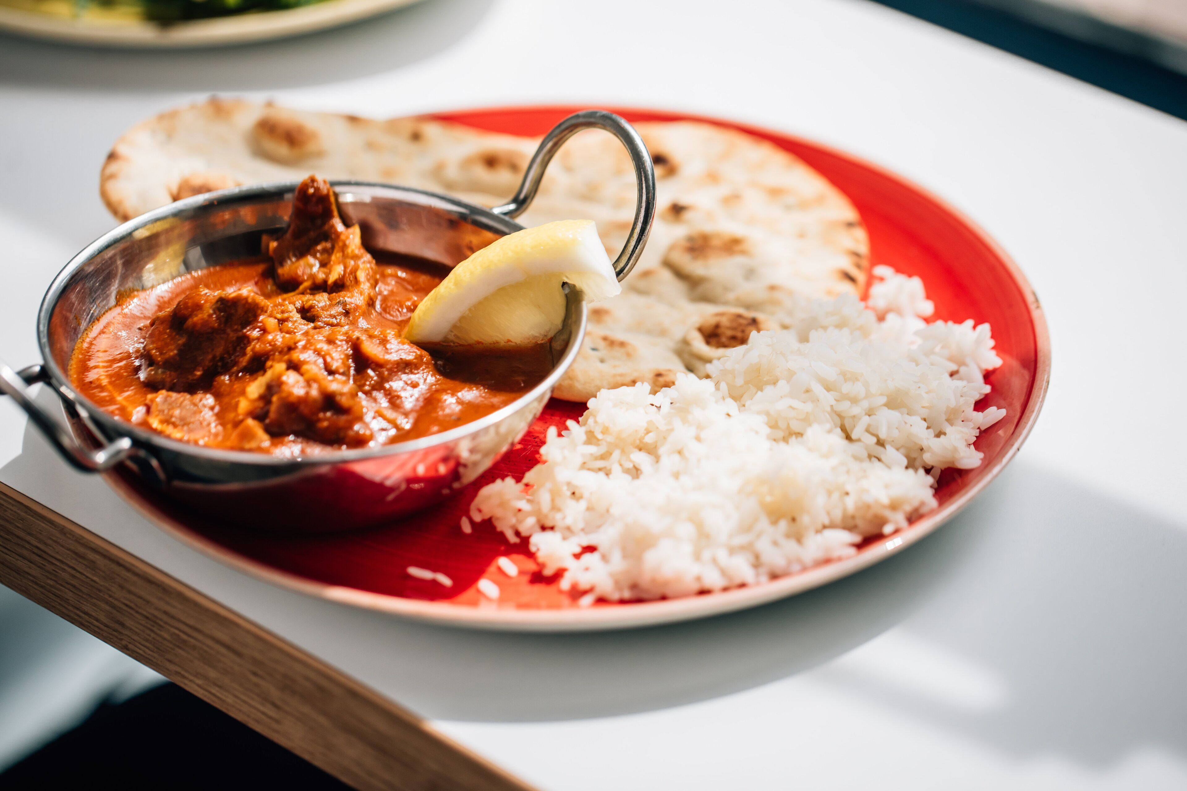 Une assiette contenant du curry, du riz et du pain plat.