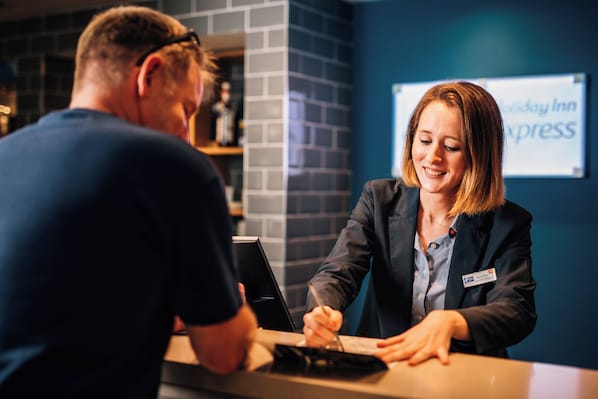 A reception desk with a name tag and a sign for Holiday Inn Express in the background. - Holiday Inn Express Belfast City by IHG (Belfast)
