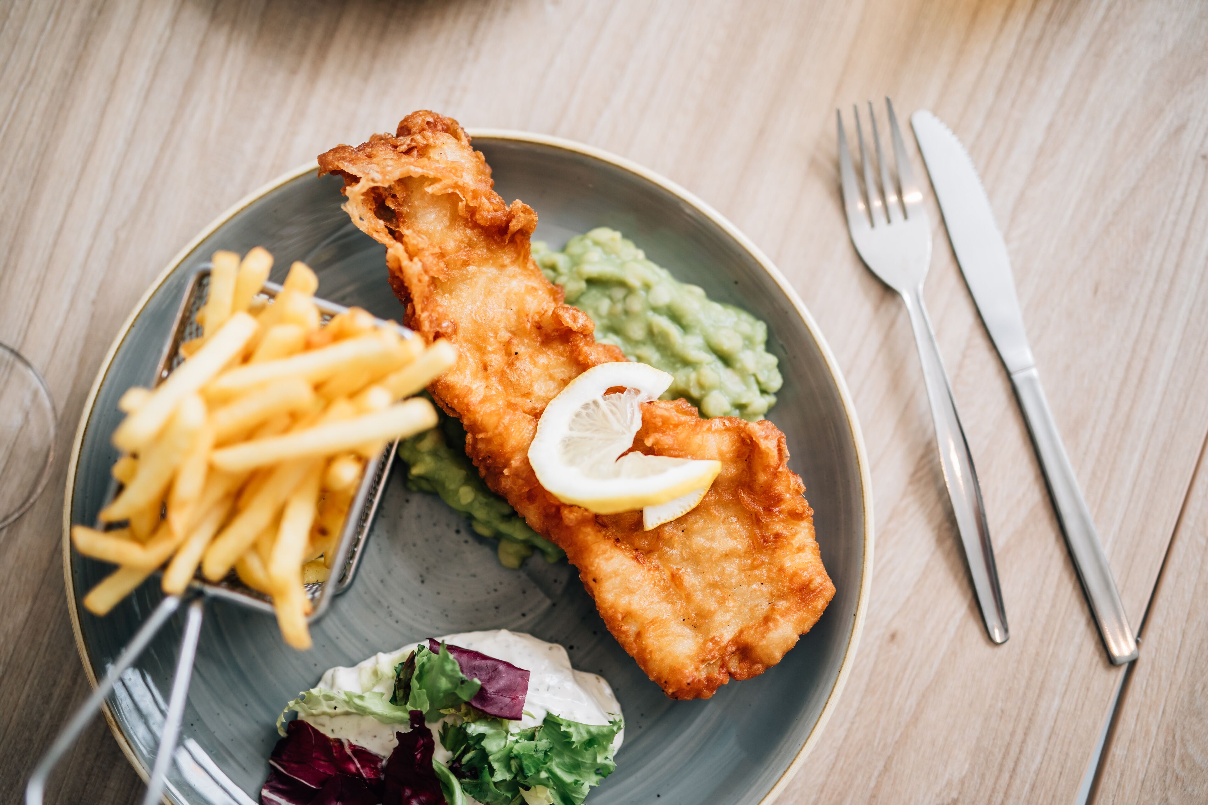Een bord met vis en friet, salade en patat.