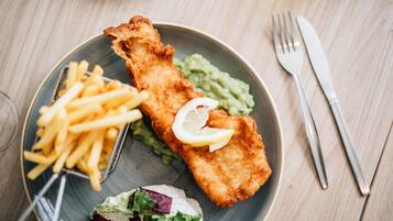 A plate with fish and chips, fries, and a salad.