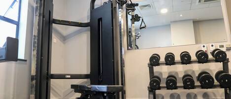 Une salle de sport équipée d’un support pour les squats, d’un banc de développé couché et d’une série de haltères.