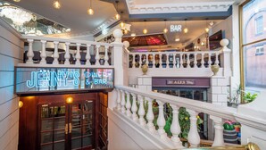 A staircase with a neon sign for Jenny's Bar, a bar sign, and a staircase railing with decorative elements. - Britannia Sachas Hotel (Manchester)