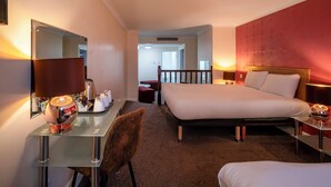 A hotel room with a bed, a desk with a lamp, a chair, and a mirror. - Britannia Sachas Hotel (Manchester)