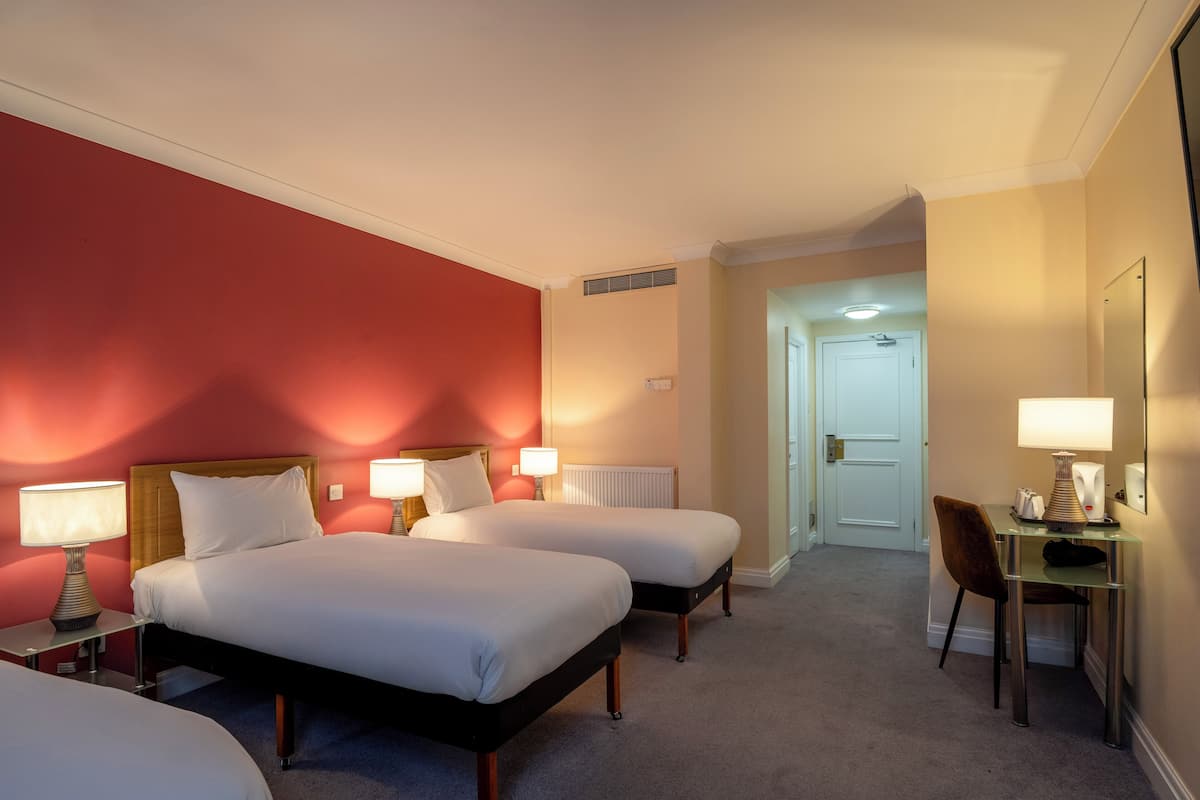 A hotel room with two beds, a desk, and a chair.