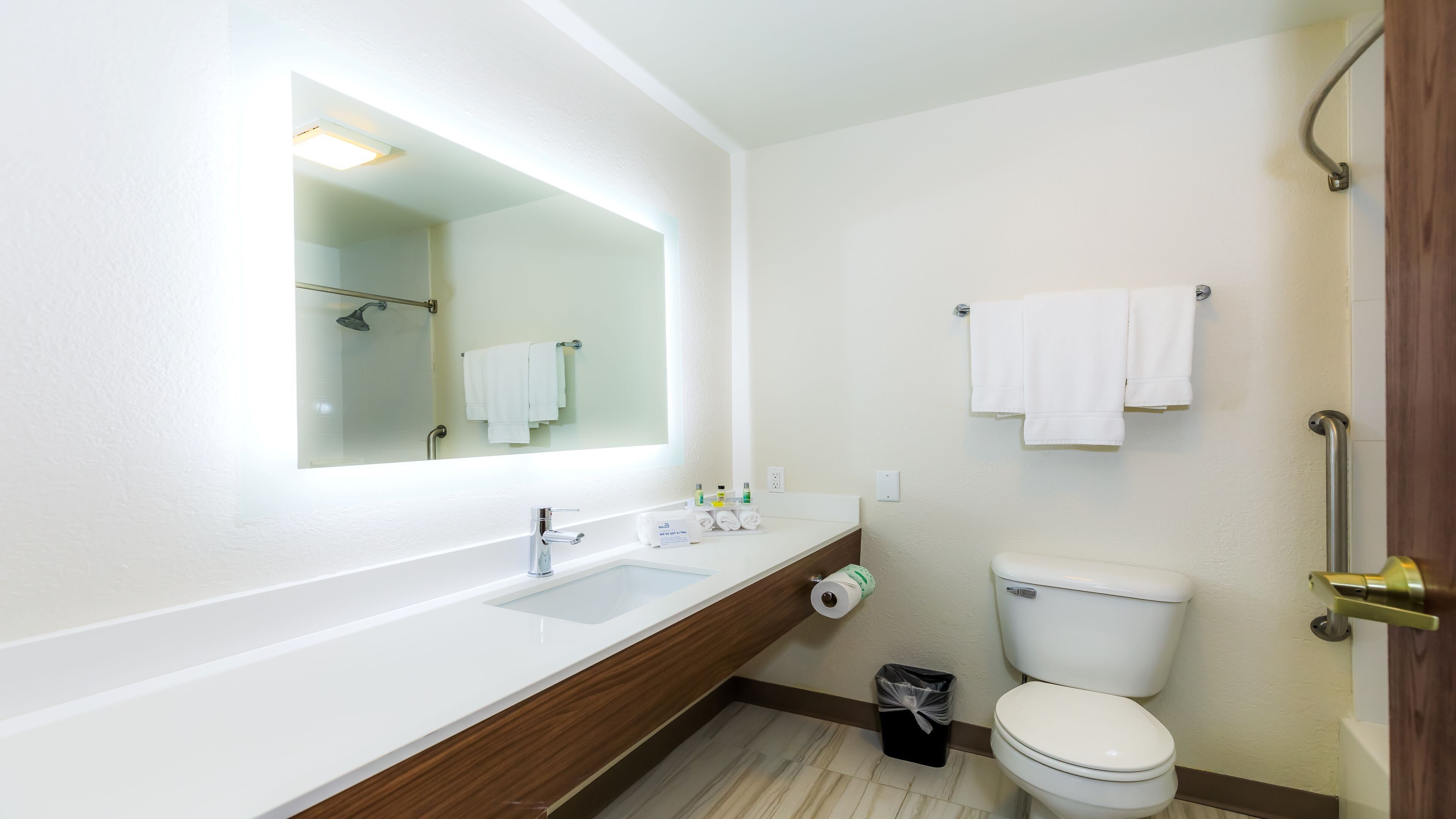 Een moderne badkamer met een wit wastafelmeubel, spiegel en toilet.