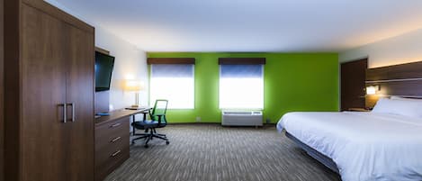Een hotelkamer met een bed, bureau, stoel en kledingkast.
