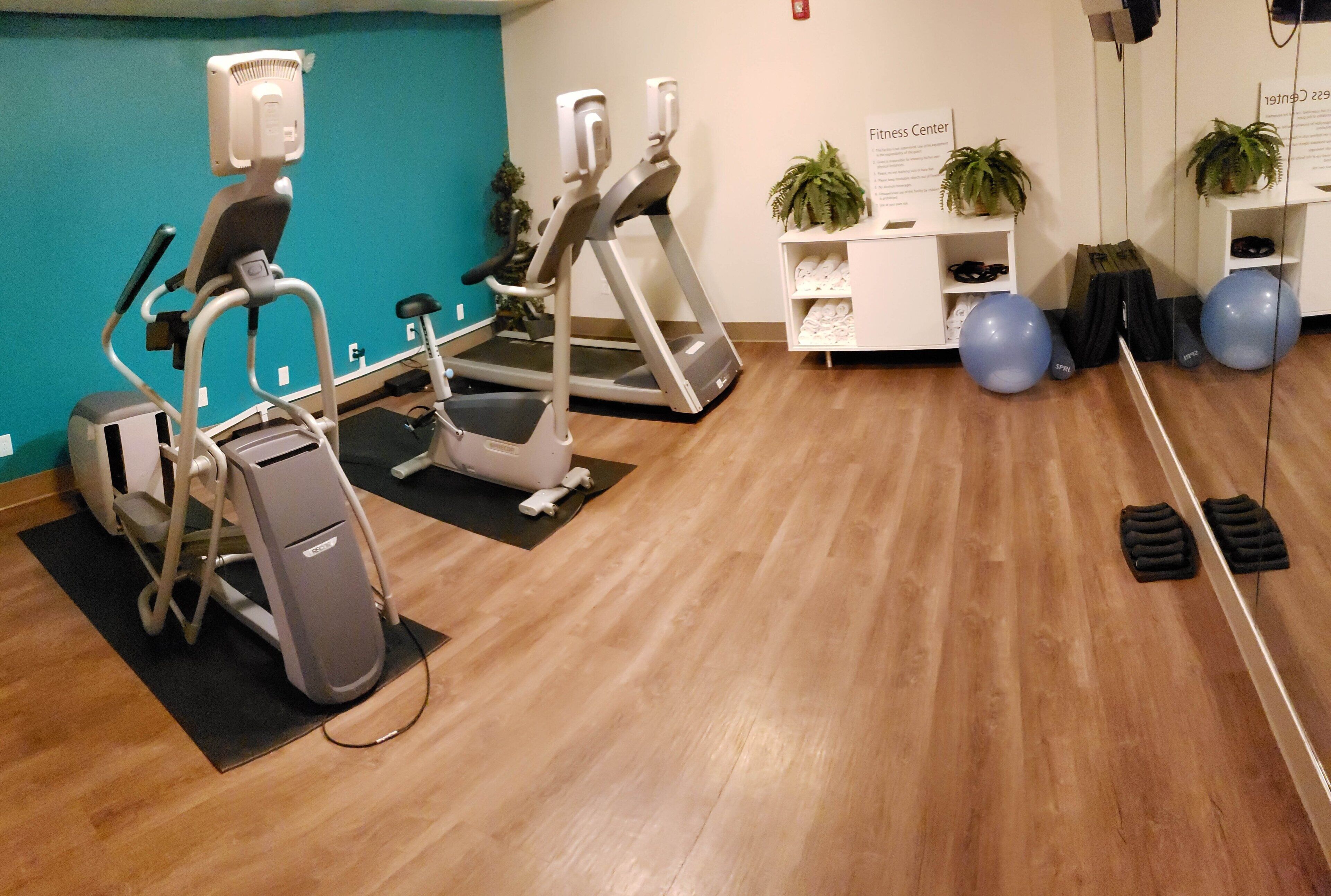 Ein Fitnessstudio mit Cardiogeräten, Übungsbällen und Laufband.