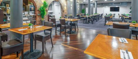 A spacious restaurant with brick arches, wooden tables, and modern lighting.