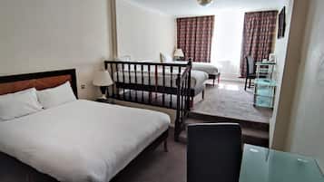 A hotel room with a large bed, a desk, a chair, and a small table.