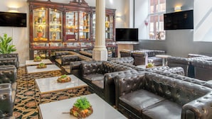 A luxurious lounge area with leather sofas, a large wooden cabinet with glass doors, and a flat-screen TV mounted on the wall.