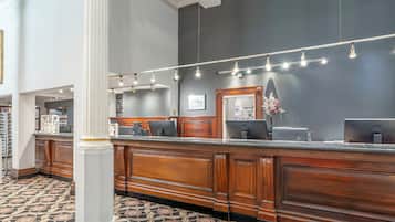 A reception area with a wooden counter, a large mirror, and a patterned carpet.