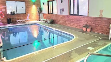 An indoor swimming pool with a wooden wall, a lifebuoy, and a sign indicating shallow water.