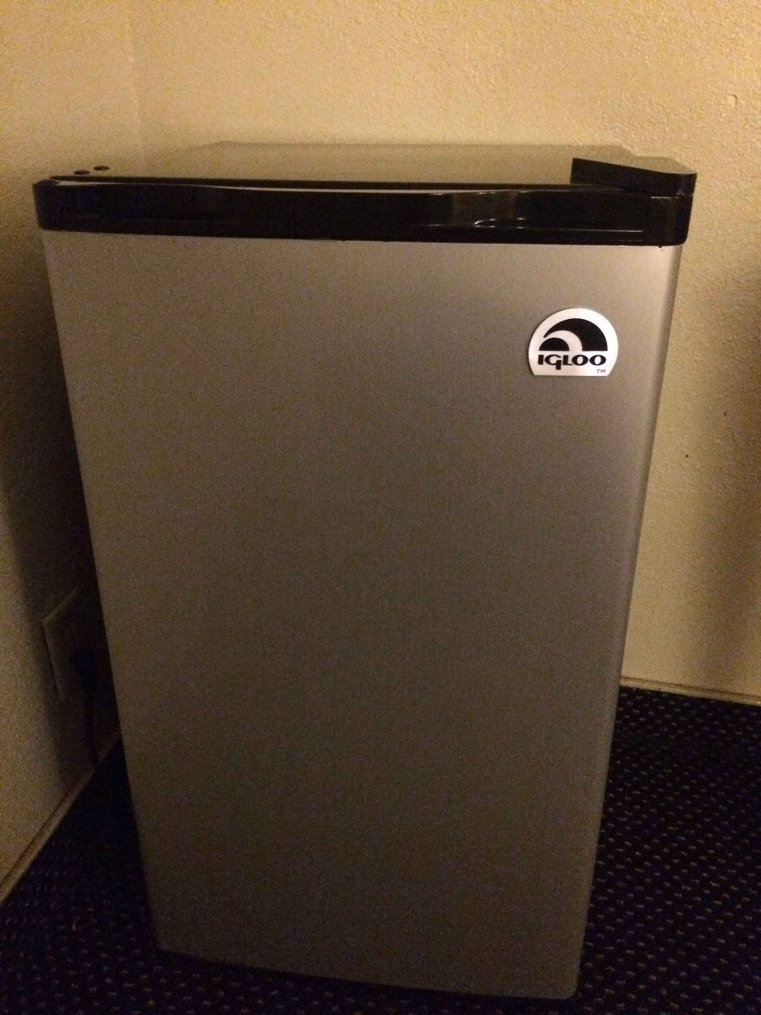 Un refrigerador compacto plateado con parte superior negra y un logotipo en el lateral.