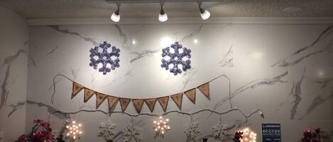 A hotel lobby with marble walls, snowflake decorations, a 'Thank You' banner, Christmas trees, and a 'No Pets' sign.