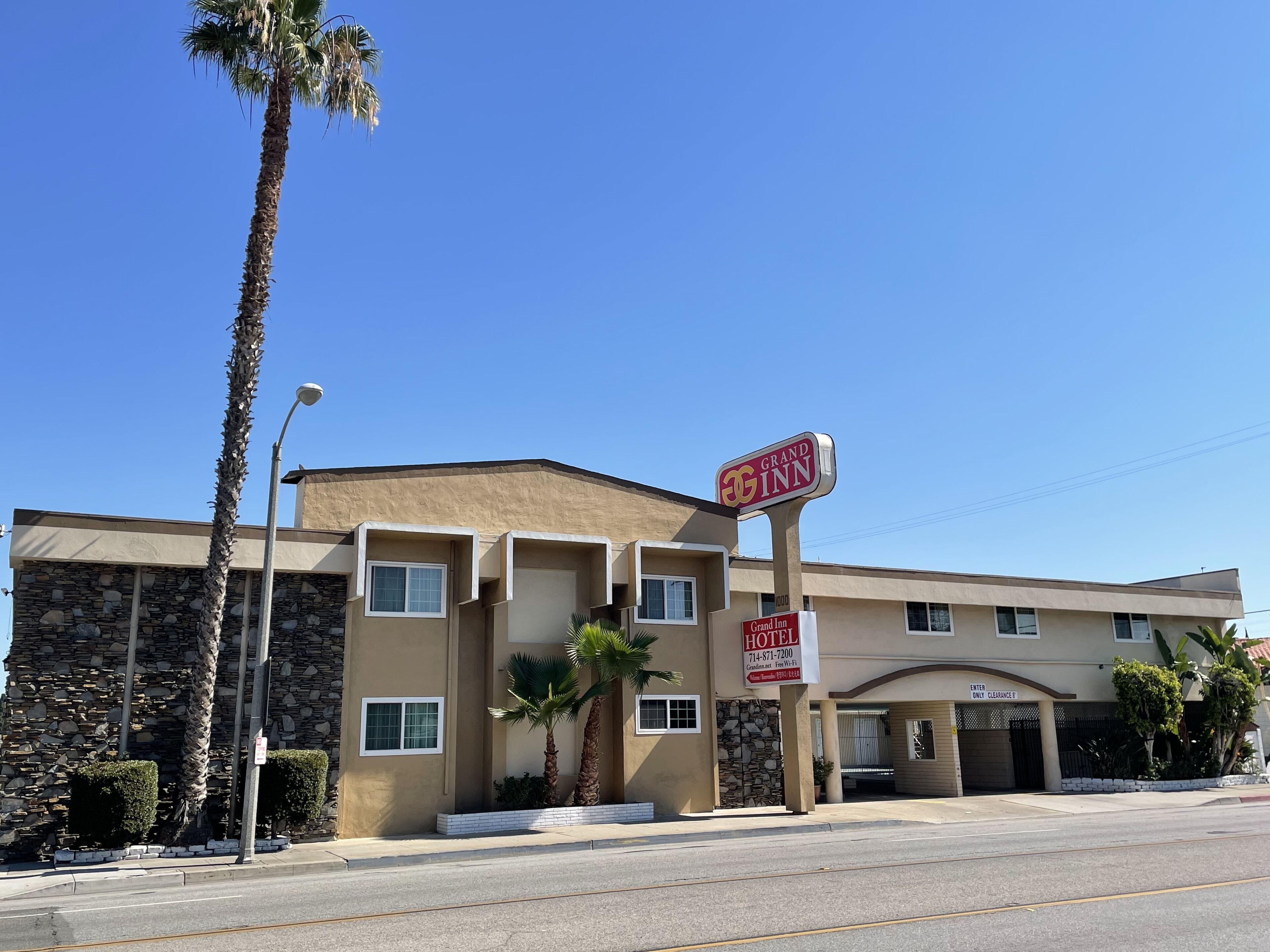 A Grand Inn Hotel with a stone facade, multiple windows, and a clear blue sky.