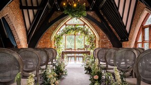 En buet gang med stole på hver side, der fører til et træaltar med blomsterdekorationer.
