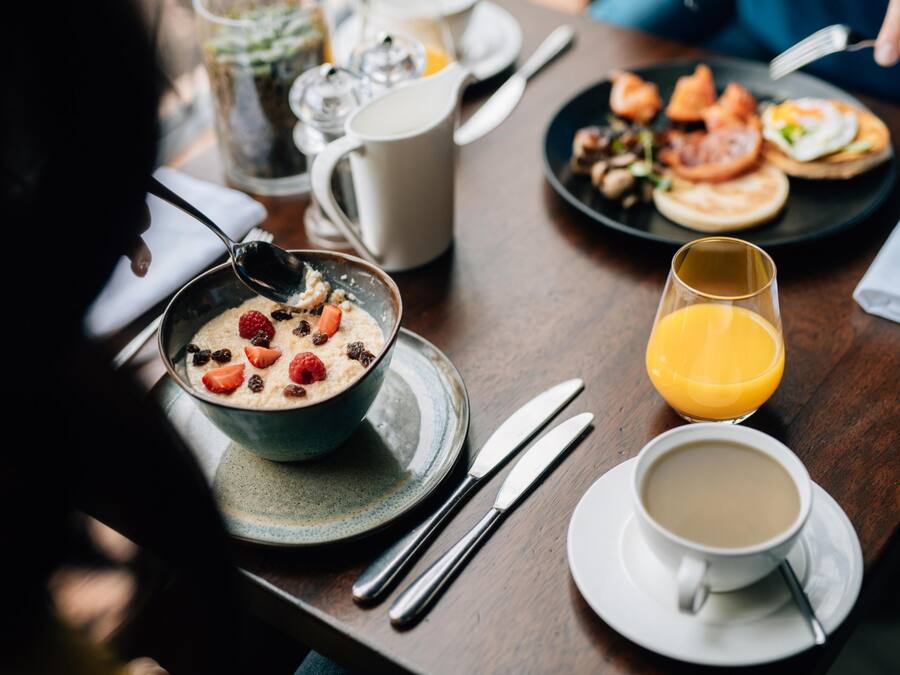 A breakfast table with a bowl of cereal, a glass of orange juice, and a cup of coffee.