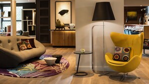 En moderne stue med en sofa, en gul lænestol, en lampe og et spiseområde i baggrunden.