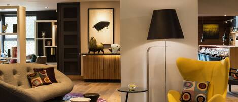 A modern living room with a sofa, a yellow armchair, a lamp, and a dining area in the background.
