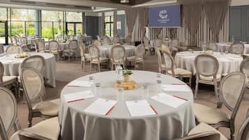 Une salle de conférence équipée de tables rondes, de chaises et d’un écran de projection sur lequel est affiché le texte « CLANDEBOYE LODGE ».