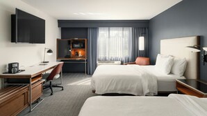 A hotel room with a bed, desk, chair, TV, and a small kitchenette. - Courtyard by Marriott Gainesville FL (Gainesville)
