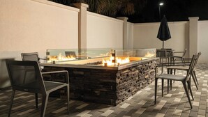 An outdoor seating area with a stone fire feature, chairs, and a table. - Courtyard by Marriott Gainesville FL (Gainesville)