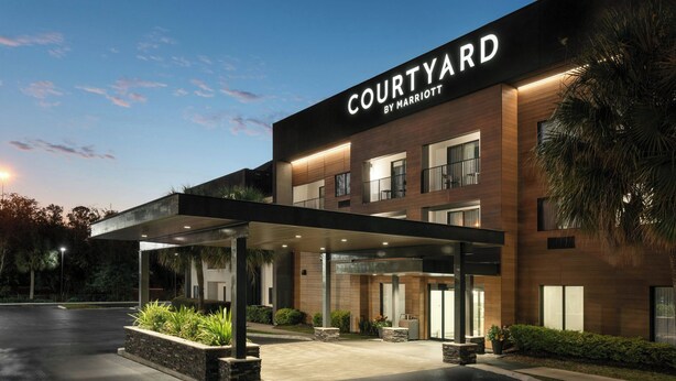 A Courtyard by Marriott hotel with a covered entrance, outdoor seating, and a well-lit facade. - Courtyard by Marriott Gainesville FL (Gainesville)