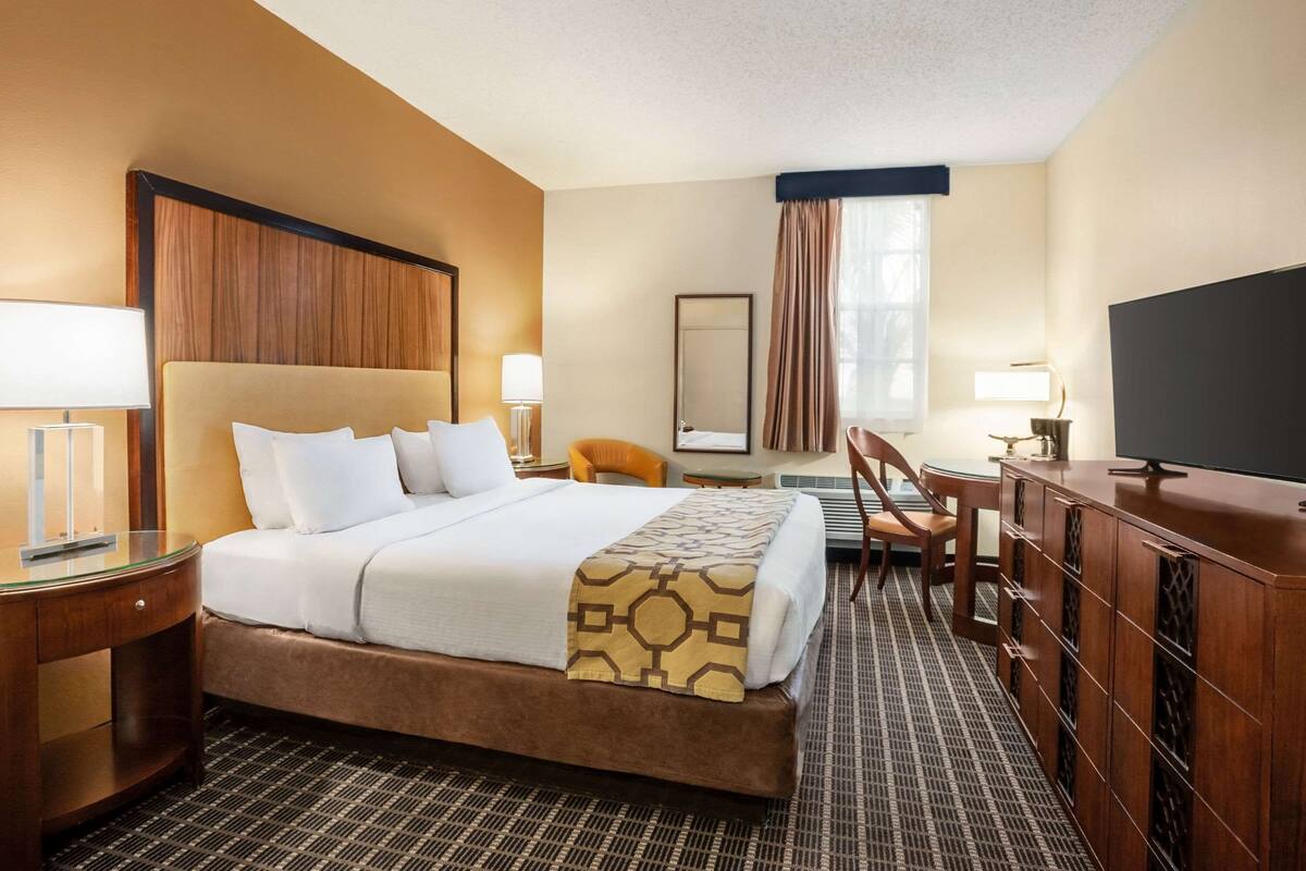 Une chambre d’hôtel avec un grand lit, un bureau, une chaise, une télévision et une armoire.