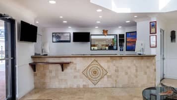 A hotel reception area with a counter, a fireplace, a television, and framed artwork on the walls.