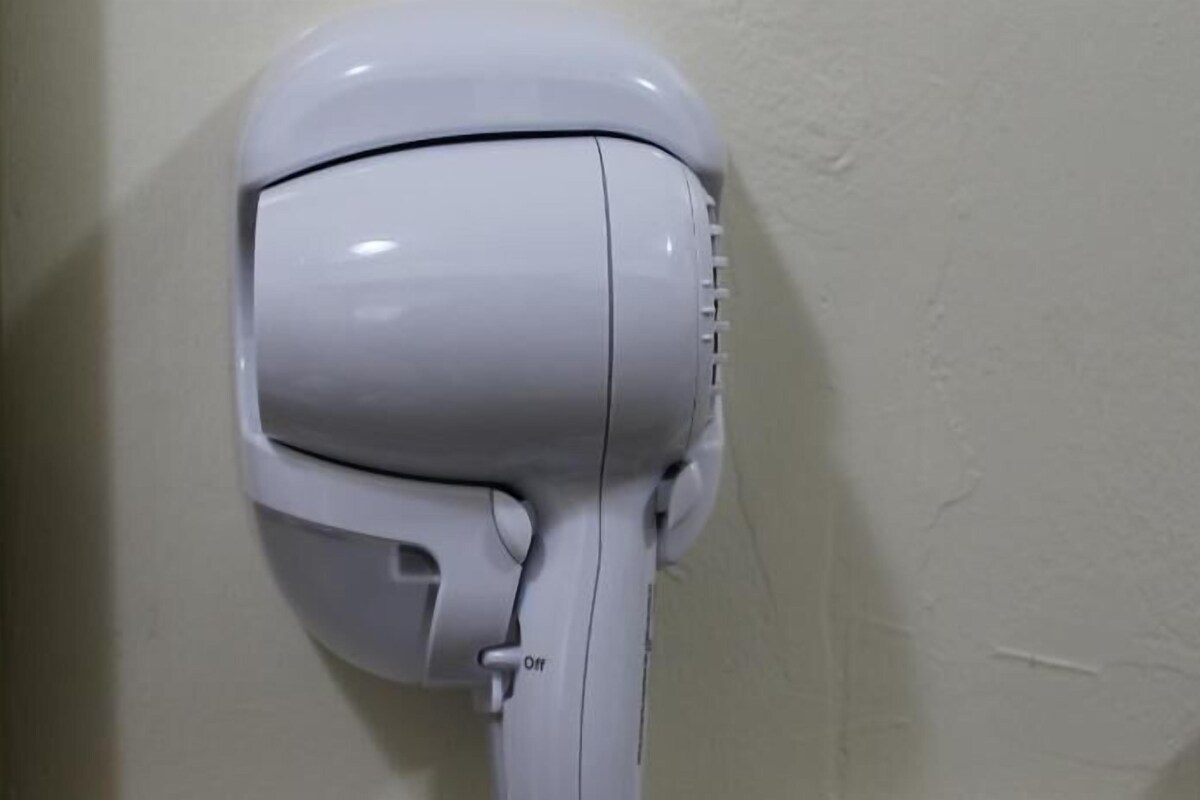 A white hair dryer mounted on a wall.