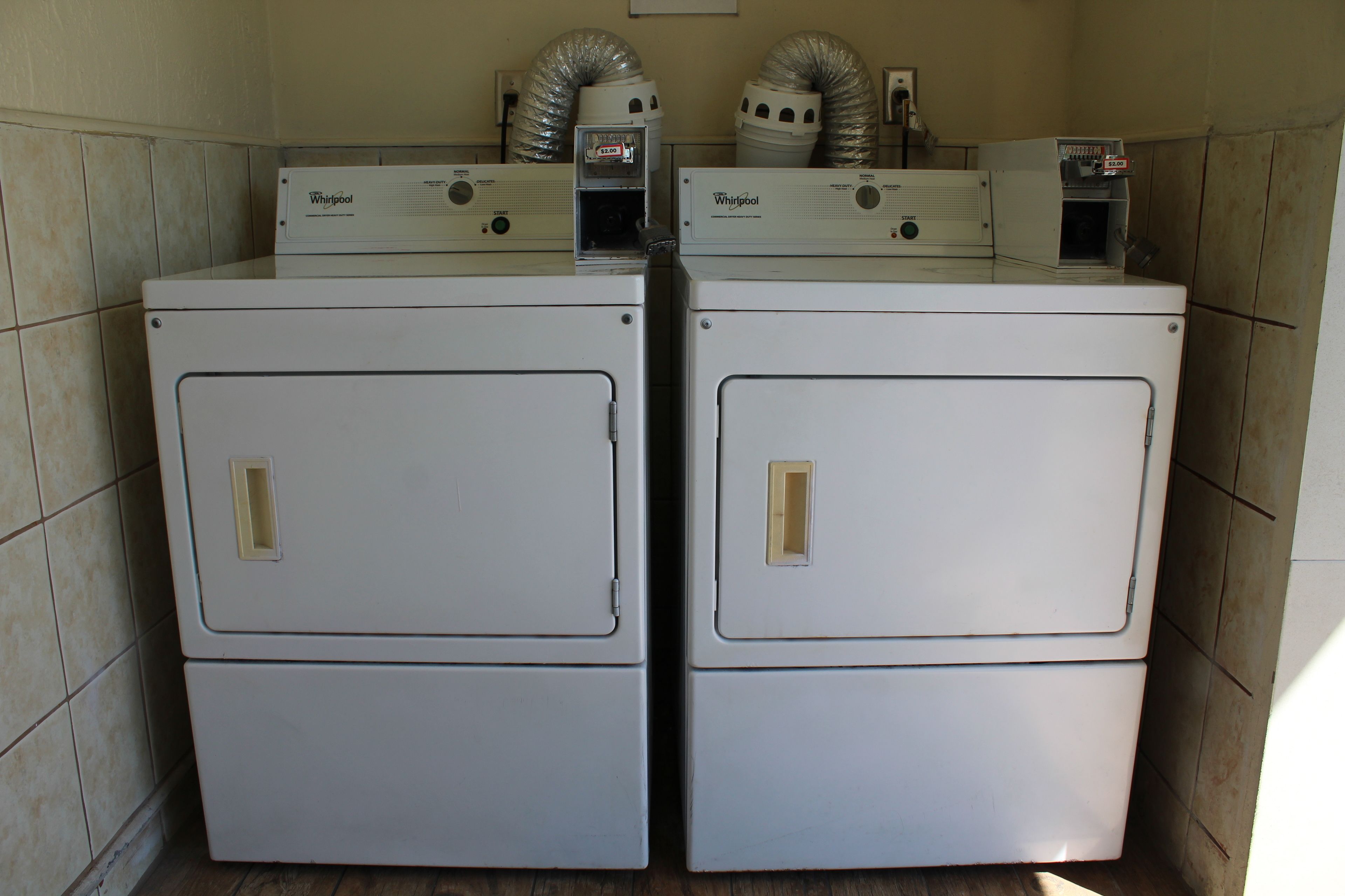 A laundry room with two stacked Whirlpool washers and dryers.