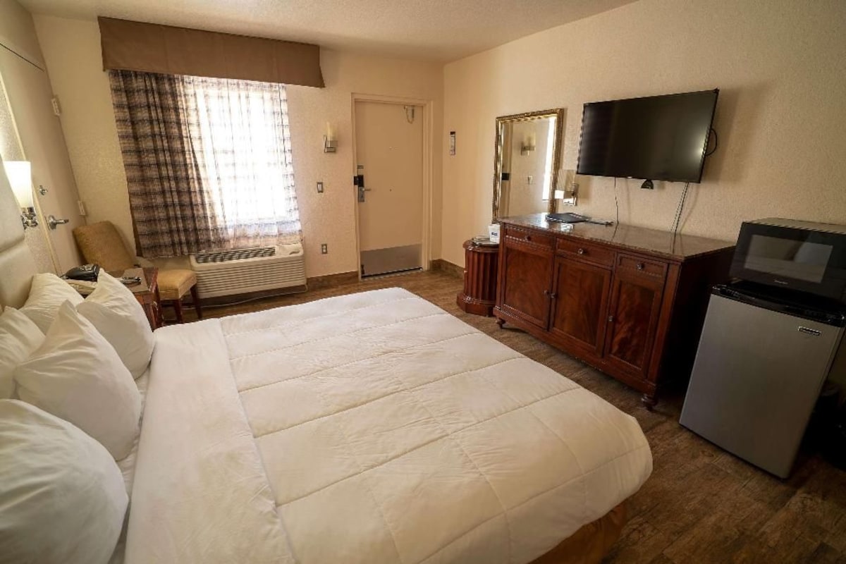 Une chambre d’hôtel avec un grand lit, une télévision, une commode et un bureau.