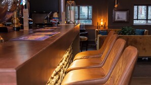 A bar area with leather barstools, a counter with a menu, and a cozy seating area with a sofa and chairs.