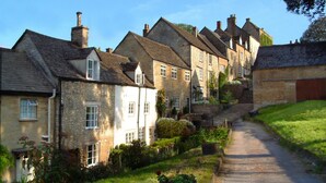 A narrow cobblestone street flanked by traditional stone buildings with steeply pitched roofs and dormer windows.