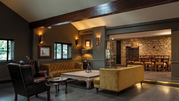A spacious living room with leather sofas, a coffee table, and a stone fireplace.