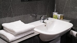 A bathroom with a white sink, a towel rack with folded towels, and toiletries on the wall. - Britannia Hotel Wolverhampton (Wolverhampton)
