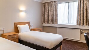 A hotel room with two beds, a nightstand, a bedside table, a window with curtains, and a radiator. - Britannia Hotel Wolverhampton (Wolverhampton)