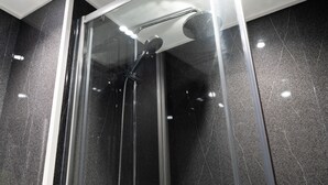 A modern shower enclosure with a glass door, a handheld showerhead, and a wall-mounted control panel. - Britannia Hotel Wolverhampton (Wolverhampton)