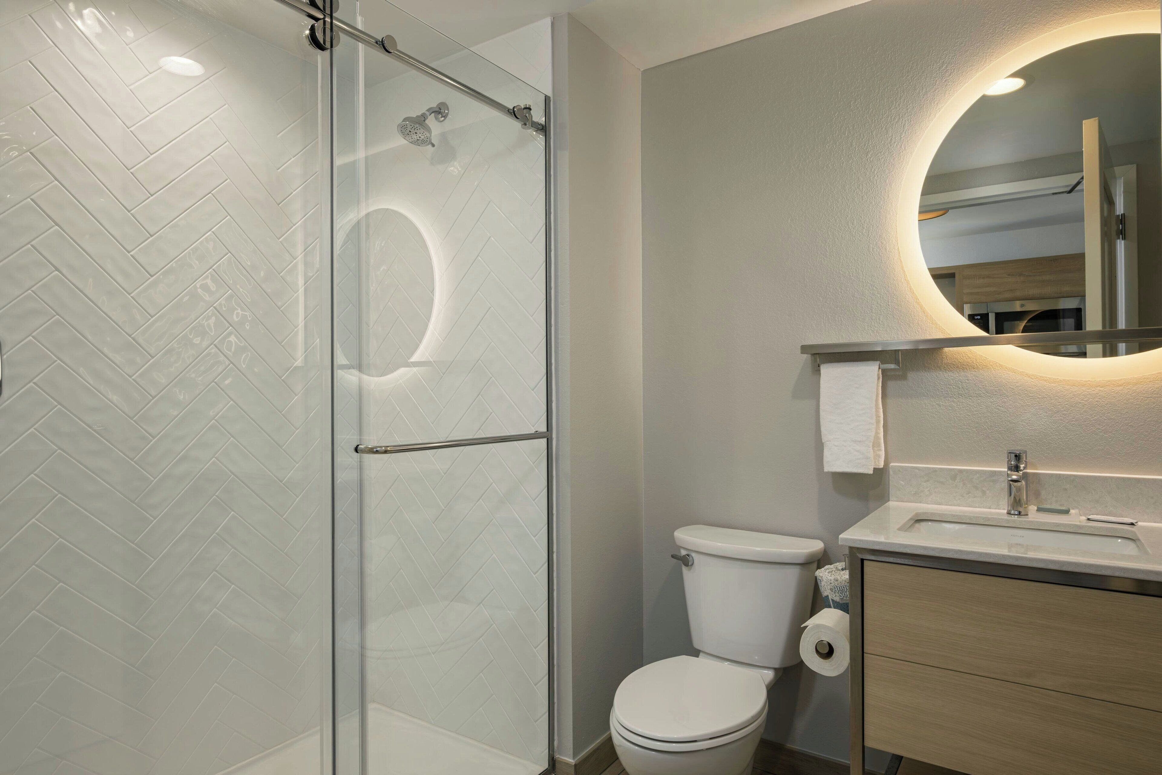 A modern bathroom with a glass-enclosed shower, a toilet, and a vanity with a mirror.