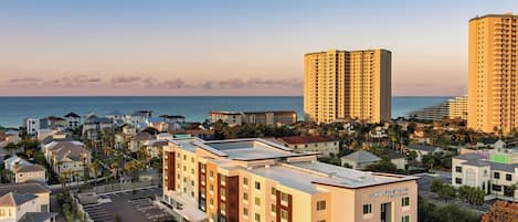 A hotel with a modern design, located near a beach with high-rise buildings in the background.