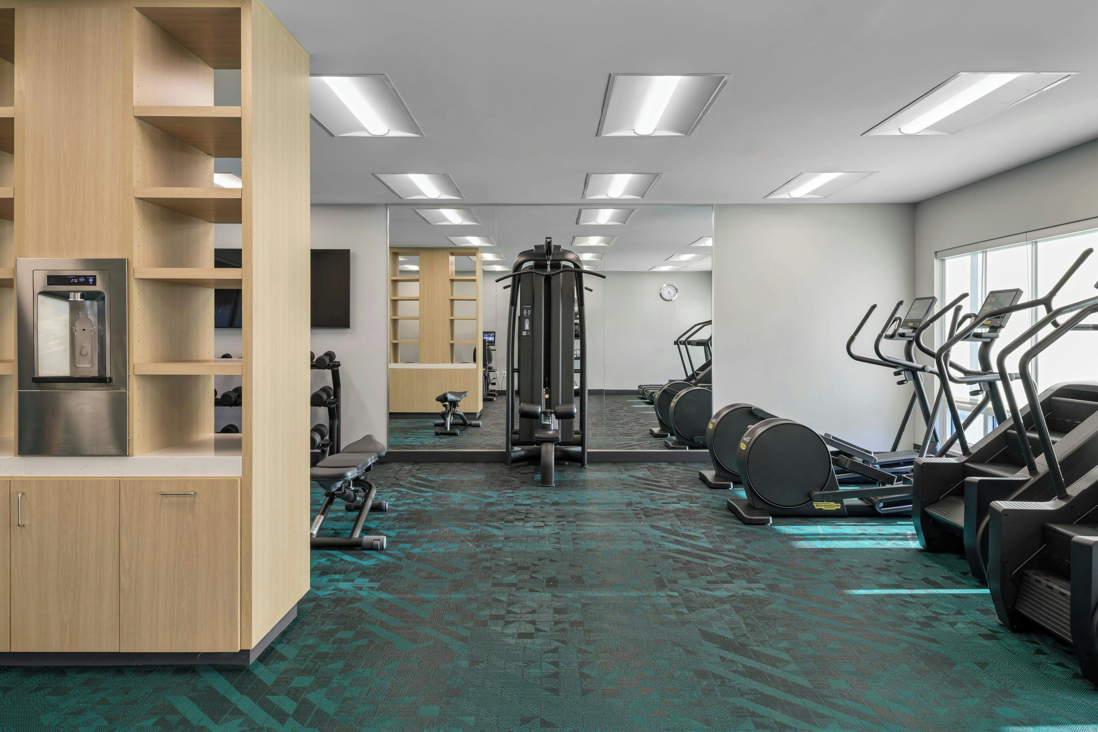 A gym with exercise equipment, a water dispenser, and a mirror.