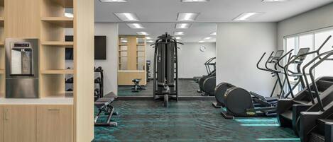 A gym with exercise equipment, a water dispenser, and a mirror.